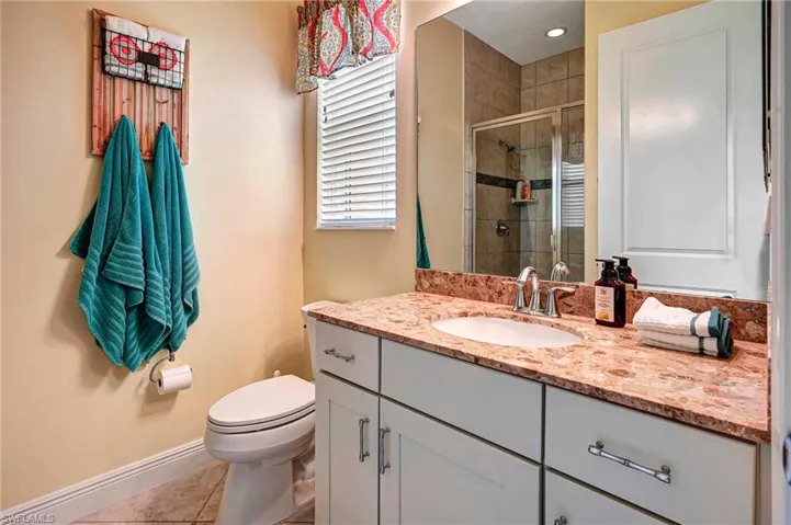 Private Guest Bathroom featuring vanity, toilet, an enclosed shower, and tile patterned floors