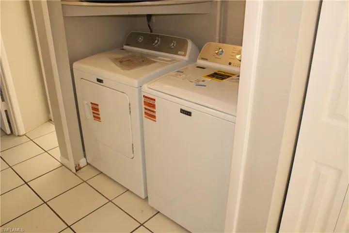 Laundry area featuring washing machine and dryer and light tile patterned floors