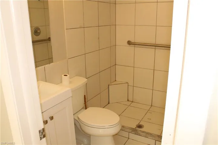Bathroom with vanity, a shower, tile patterned flooring, and tile walls