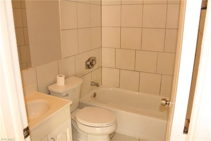 Bathroom with vanity,  shower combination, and tile walls