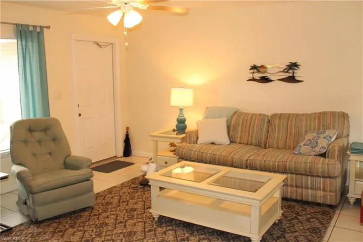 Tiled living area featuring ceiling fan and baseboards