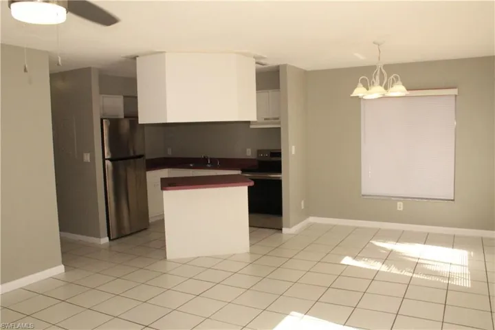 Kitchen featuring appliances with stainless steel finishes, pendant lighting, dark countertops, white cabinets, and a chandelier