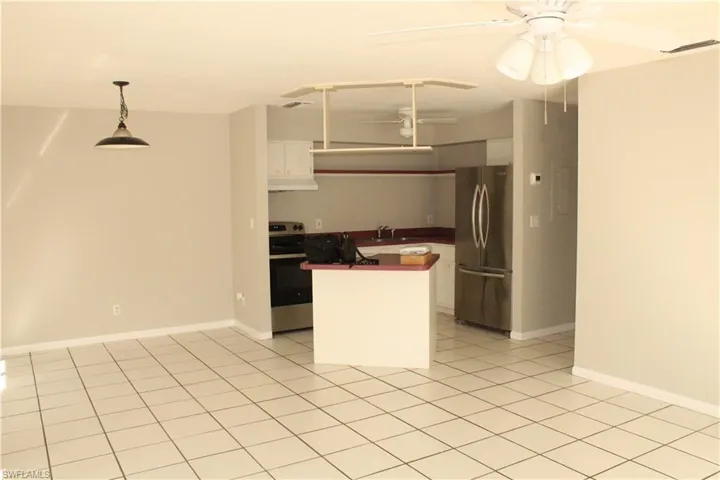 Kitchen with appliances with stainless steel finishes, dark countertops, pendant lighting, white cabinets, and a kitchen island