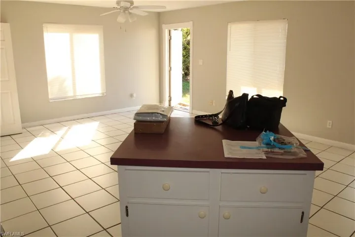 Kitchen with light tile patterned floors, white cabinets, dark countertops, and a ceiling fan