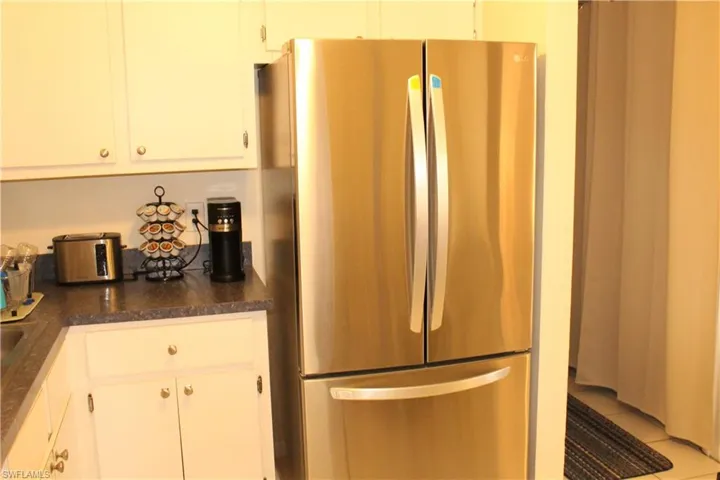 Kitchen featuring freestanding refrigerator, dark countertops, and white cabinets