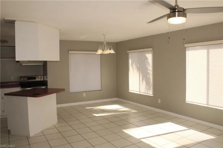 Kitchen featuring electric range, white cabinetry, dark countertops, decorative light fixtures, and a chandelier