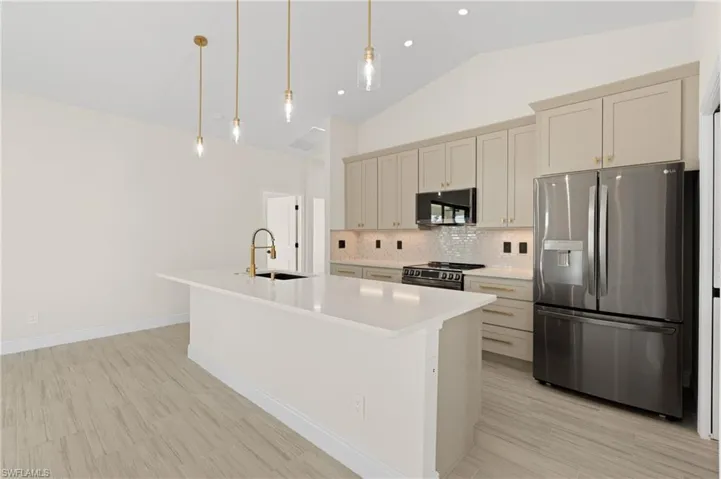Kitchen featuring upgraded LG appliancesf, a kitchen island with sink, pendant lighting, and lofted ceiling