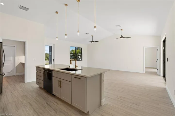 Kitchen with sink, ceiling fan, gray cabinets, black dishwasher, and a quartz island with sink
