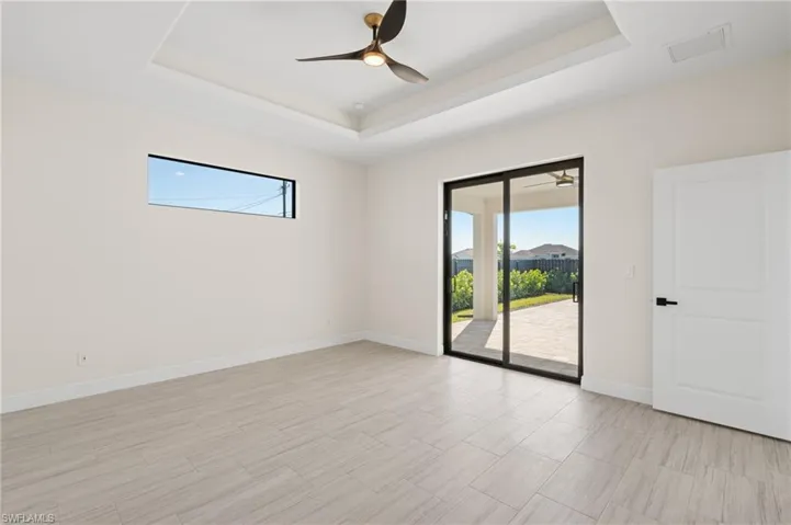 Spare room with a tray ceiling, plenty of natural light, and ceiling fan