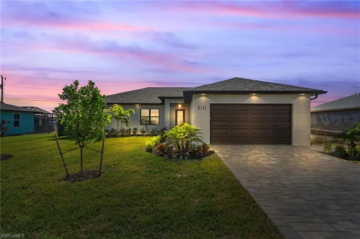Twilight view of front of house with a yard and a garage