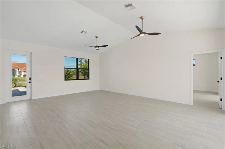 Unfurnished living room with high vaulted ceiling, ceiling fan, light Italian tile floors, and a wealth of natural light