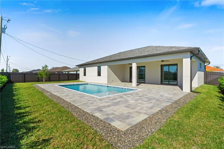 View of swimming pool with a yard, ceiling fan, and a patio area
