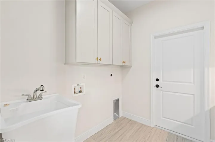 Laundry room featuring cabinets, sink, hookup for a washing machine, hookup for an electric dryer, and light Italian tile floors