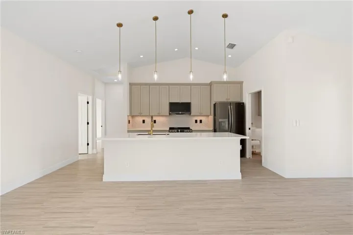 Kitchen featuring appliances with stainless steel finishes, a kitchen island with sink, pendant lighting, and sink