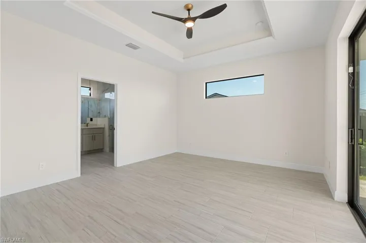 Unfurnished room with ceiling fan, light Italian tile flooring, and a tray ceiling