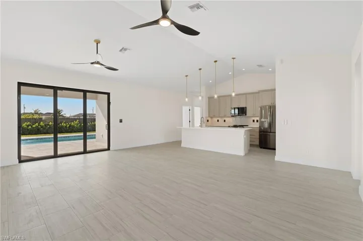 Unfurnished living room with ceiling fan, lofted ceiling, and sink