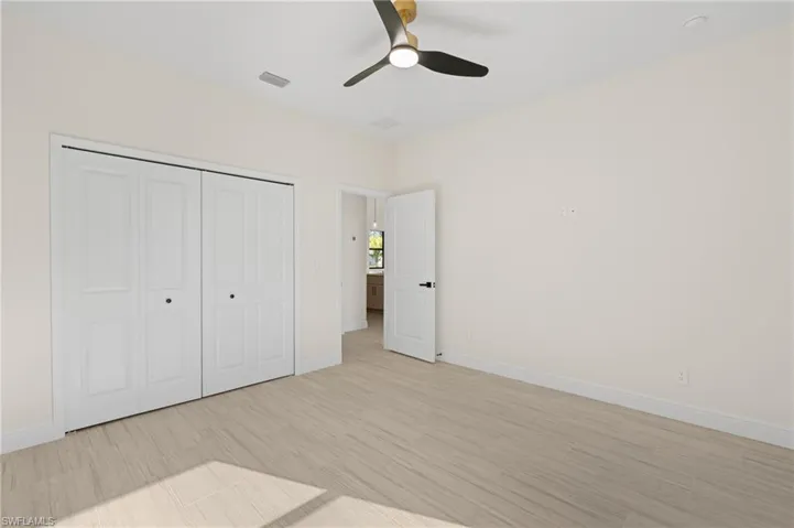 Unfurnished bedroom with a closet, light Italian Tile flooring, and ceiling fan