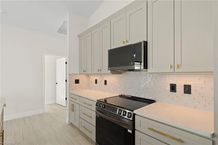 Kitchen featuring light quartz countertops, black range with electric stovetop, and backsplash