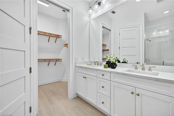 Full bathroom featuring double vanity, a stall shower, and light wood-type flooring