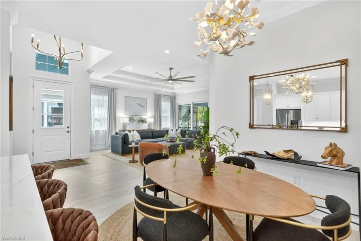 Dining space featuring a chandelier, a tray ceiling, wood finished floors, ornamental molding, and recessed lighting
