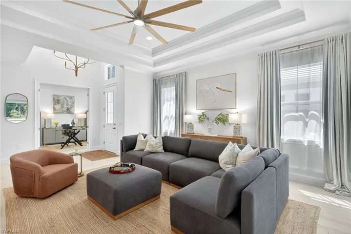 Living room with a tray ceiling, ornamental molding, a ceiling fan, wood finished floors, and recessed lighting