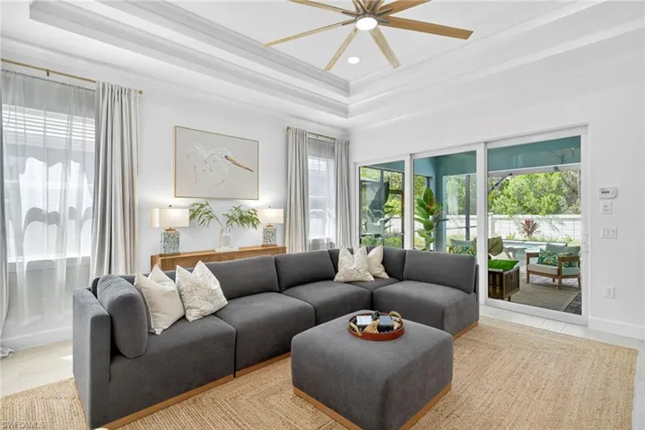Living area with a tray ceiling, recessed lighting, crown molding, wood finished floors, and a ceiling fan