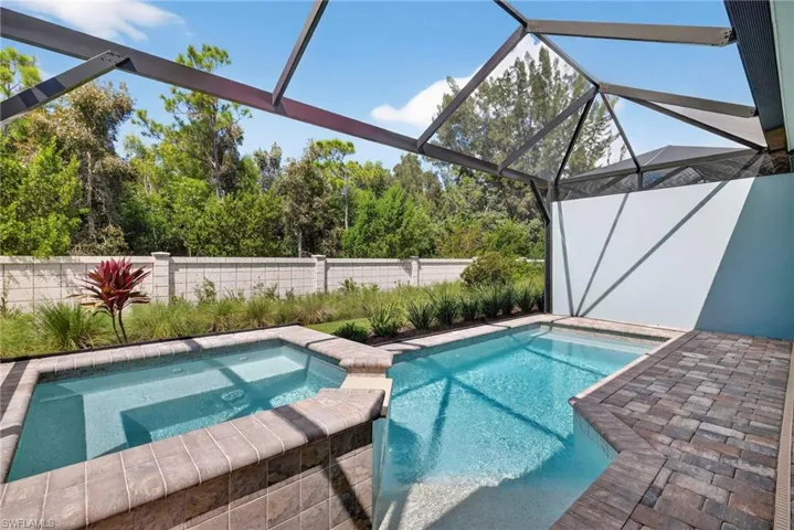 View of swimming pool with a sunroom, a patio, glass enclosure, a fenced backyard, and a pool with connected hot tub