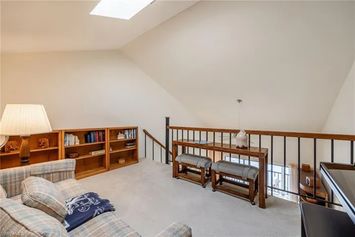 Sitting room featuring vaulted ceiling with skylight and light colored carpet