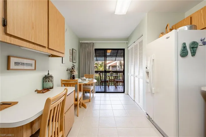 Kitchen with white refrigerator with ice dispenser and light tile patterned floors