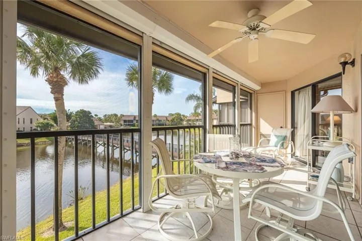 Sunroom with ceiling fan and a water view