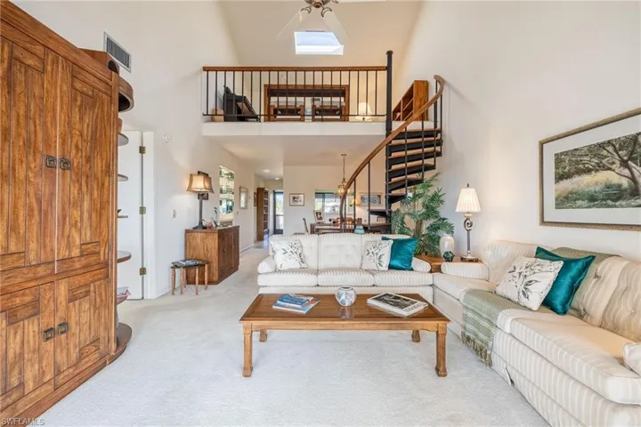 Living room featuring light carpet, high vaulted ceiling, and ceiling fan