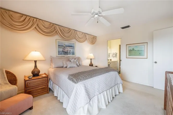 Carpeted bedroom with ensuite bathroom and ceiling fan