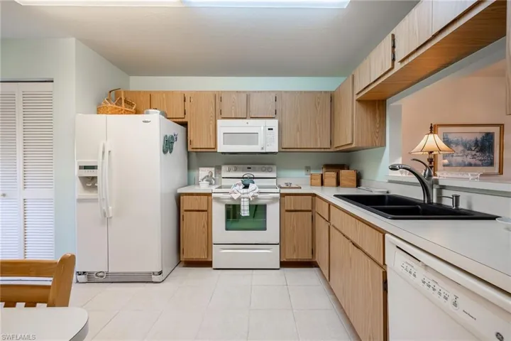Kitchen featuring light tile patterned flooring, white appliances, sink, and light brown cabinets