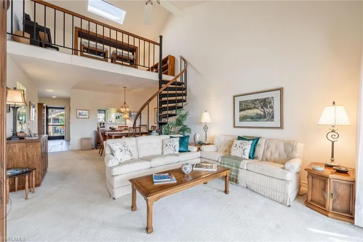 Carpeted living room featuring a towering ceiling and ceiling fan