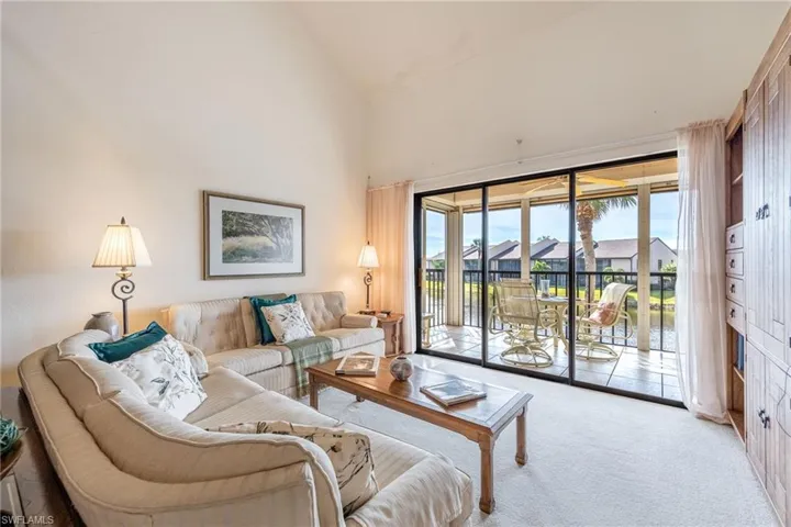 Carpeted living room featuring high vaulted ceiling