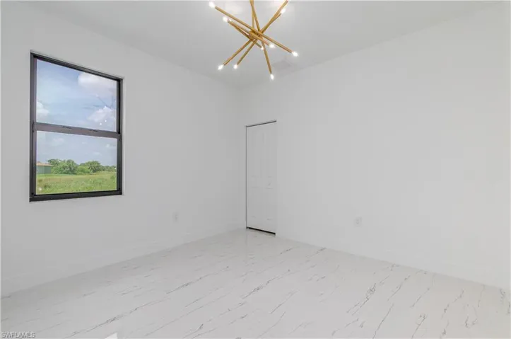 Spare room featuring a chandelier and light marble finish floors