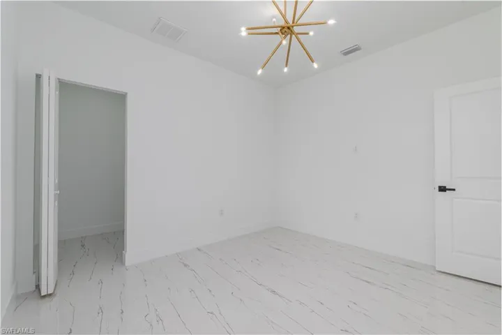 Spare room with a chandelier and marble look tiles