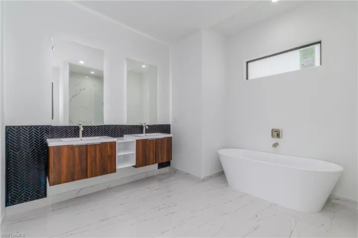 Bathroom with double vanity, a freestanding bath, marble finish flooring, recessed lighting, and a marble finish shower