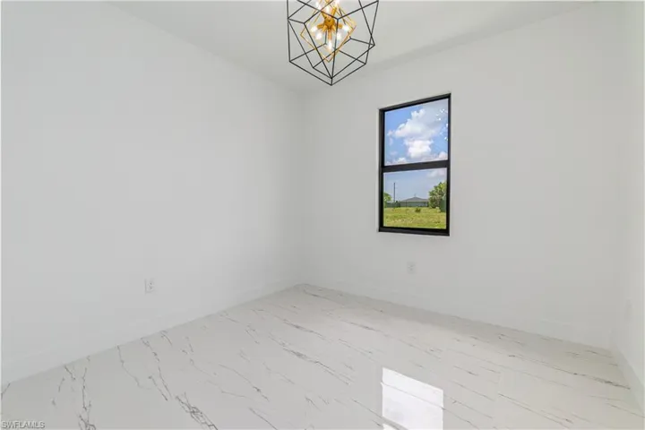 Unfurnished room featuring light marble finish flooring and a chandelier