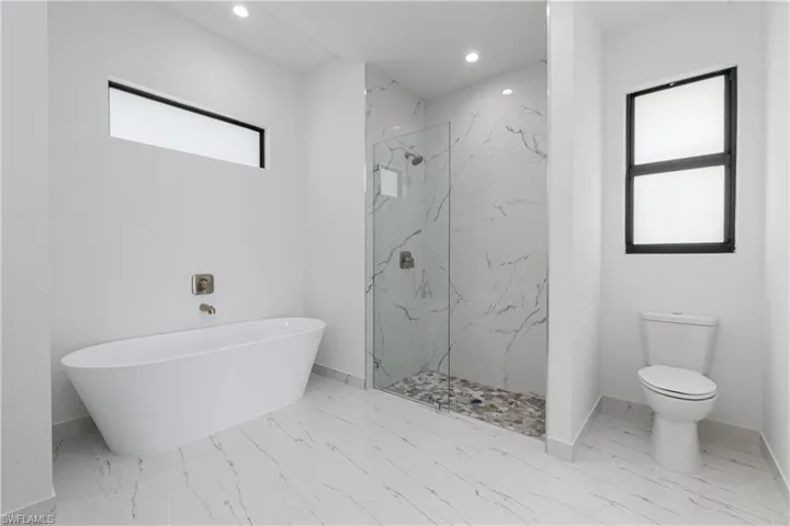 Full bath featuring marble finish flooring, a soaking tub, recessed lighting, and a marble finish shower