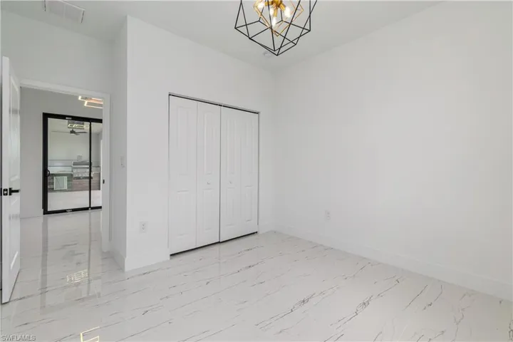 Unfurnished bedroom with light marble finish flooring, a chandelier, and a closet