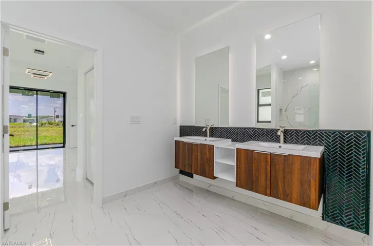 Full bathroom featuring double vanity, marble finish floors, and recessed lighting