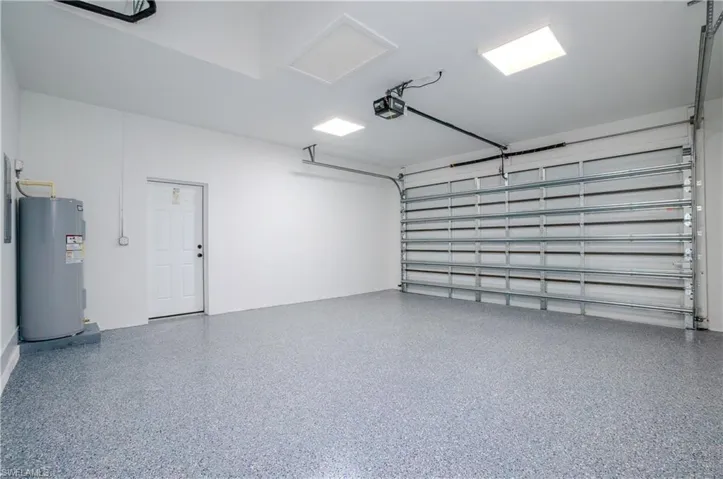 Garage featuring electric water heater and a garage door opener