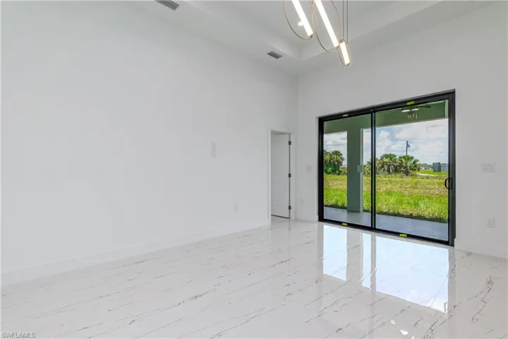 Unfurnished room with light marble finish flooring, a chandelier, a towering ceiling, and a raised ceiling