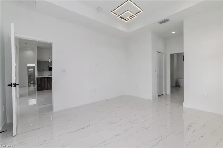Unfurnished room featuring recessed lighting, a raised ceiling, light marble finish flooring, a chandelier, and a smoke detector