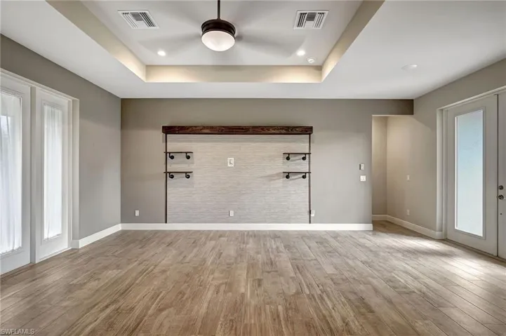 Great room featuring ceiling fan, french doors, wood plank tiled floors, and a coffered ceiling