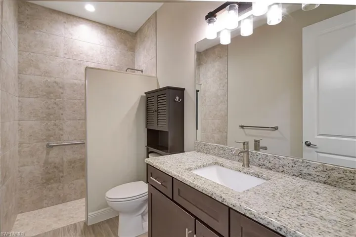 Bathroom featuring  wood plank tiled floors, vanity, and a tile shower