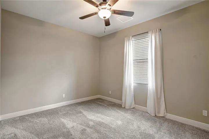 Carpeted guest bedroom featuring ceiling fan