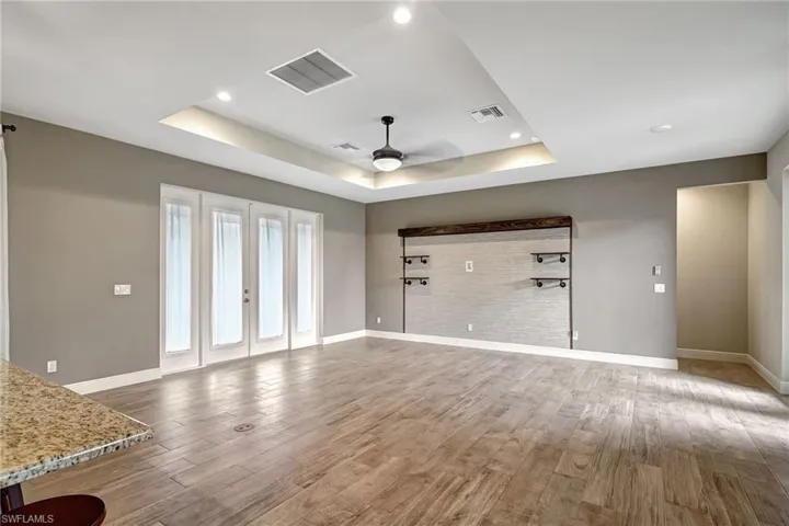 Living room with a Coffered ceiling, wood plank tiled flooring, ceiling fan, and french doors