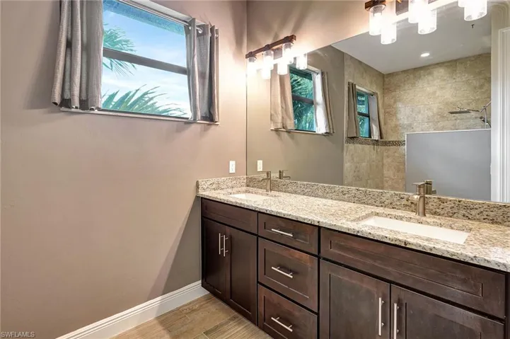 Bathroom featuring tiled shower, vanity, and wood plank tiled flooring